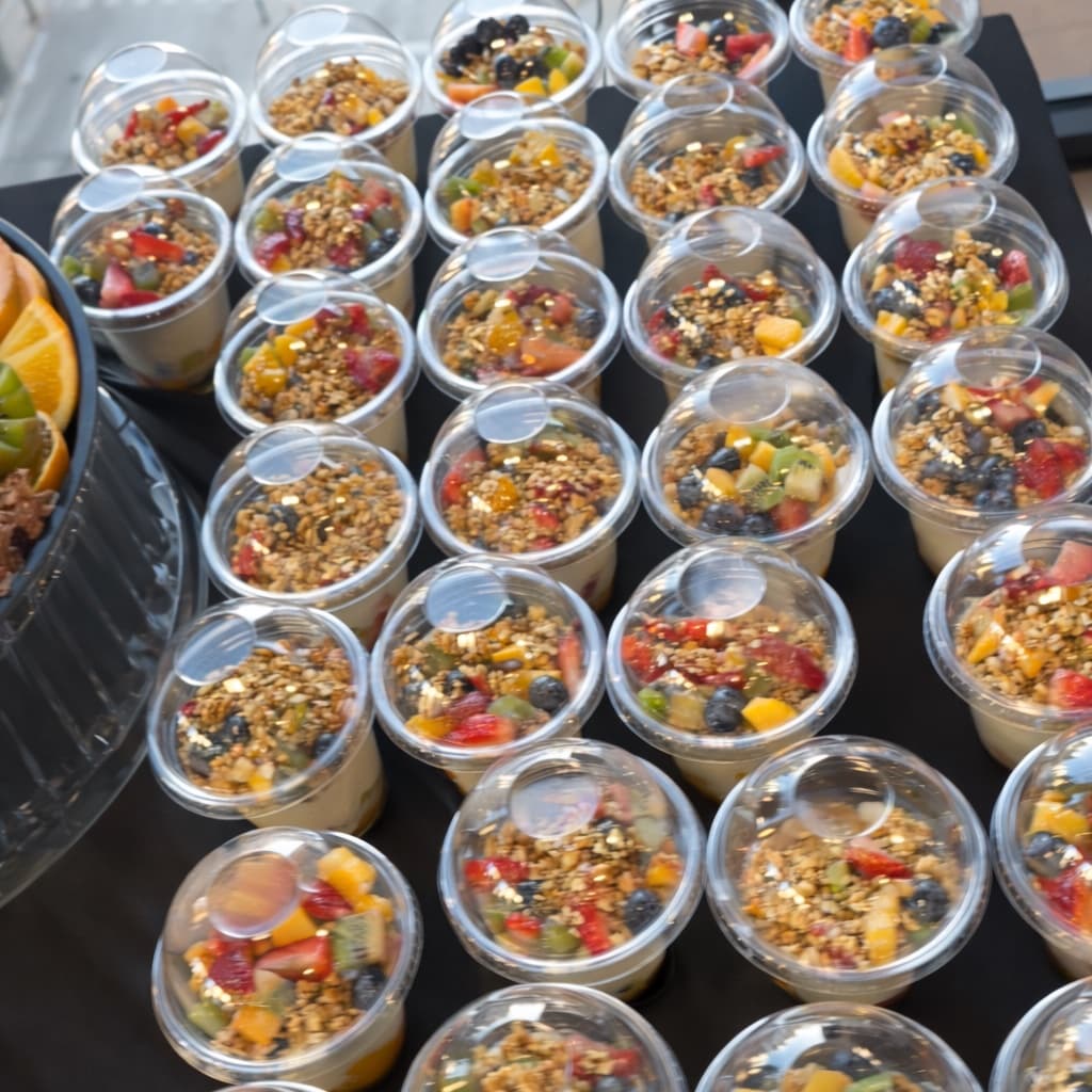 Rows of yogurt parfait cups topped with granola, berries, and mango