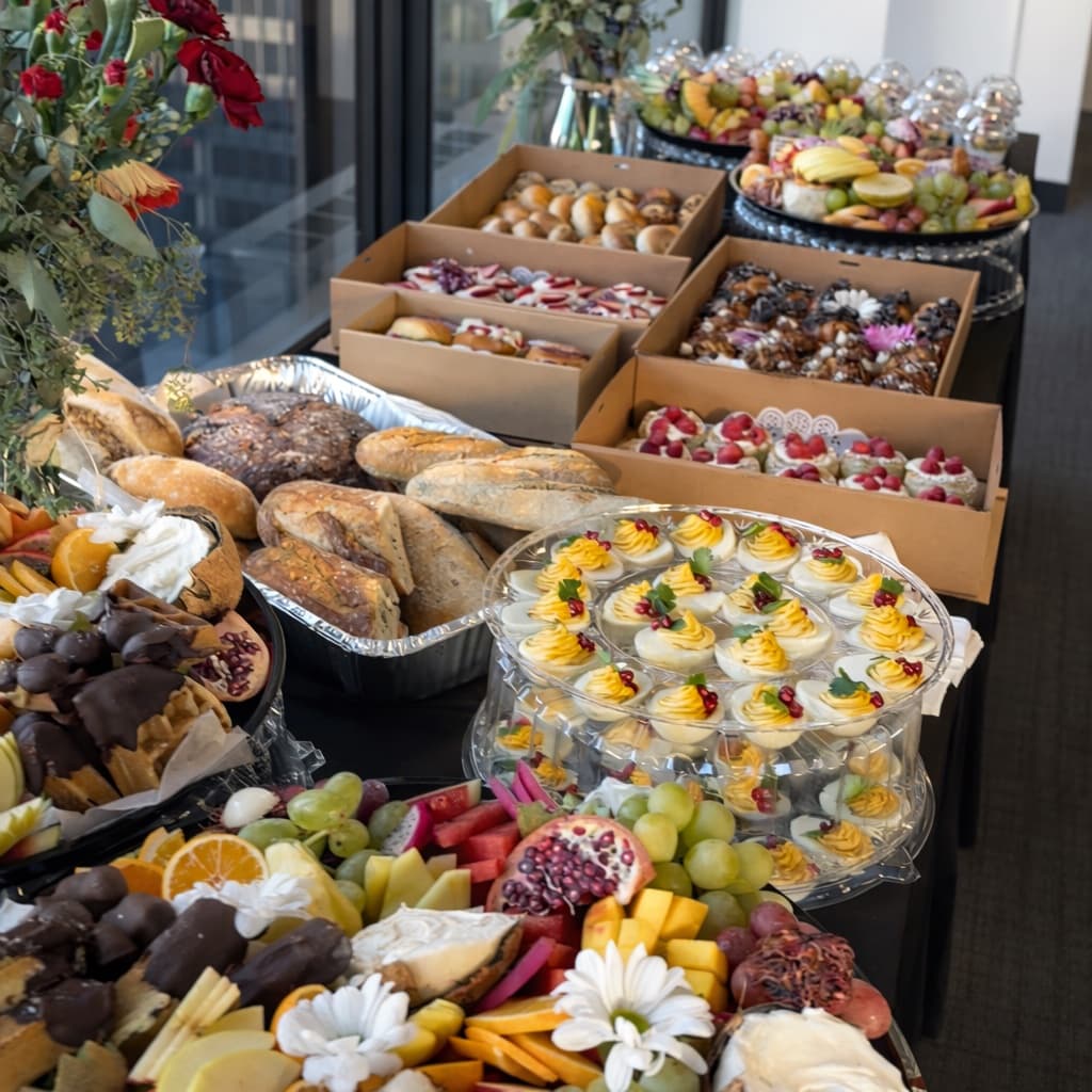 Full Erik's catering buffet — sandwiches, charcuterie, fruit, deviled eggs — set up at a Chicago office window